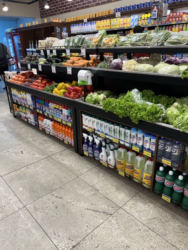 Banca de parede com verduras e legumes na parte superior e produtos de limpeza embaixo.