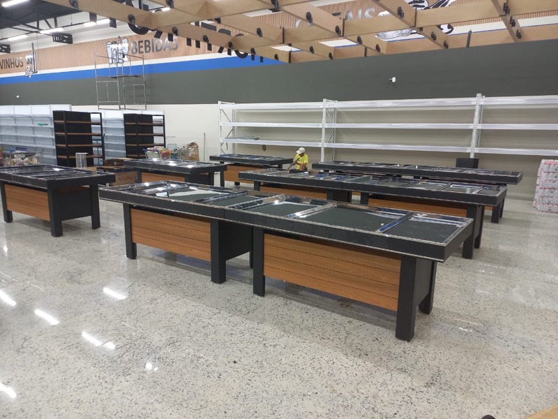 Fileira de bancas de centro premium com frente ripada em padrão madeira, recém-instaladas em loja.
